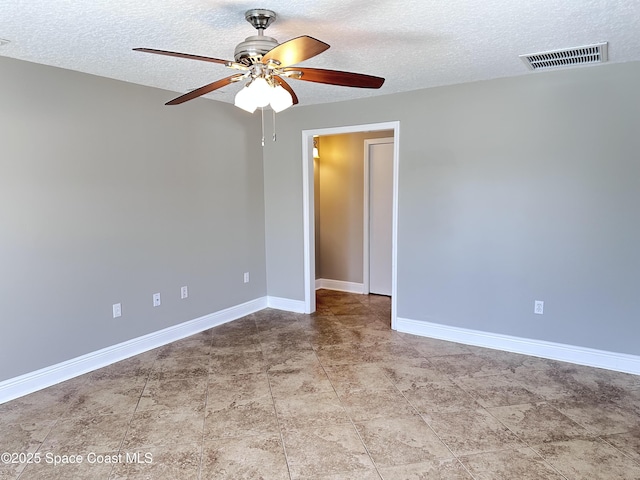 spare room featuring visible vents, baseboards, a textured ceiling, and a ceiling fan