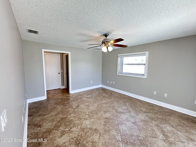 spare room featuring tile patterned floors, visible vents, a textured ceiling, baseboards, and ceiling fan