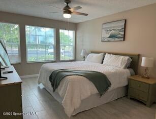 bedroom with ceiling fan, light hardwood / wood-style flooring, and multiple windows