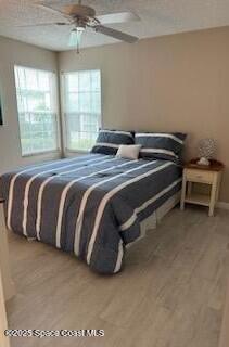 bedroom with ceiling fan, light hardwood / wood-style floors, and multiple windows