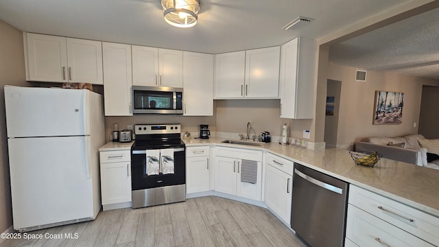 kitchen featuring white cabinetry, sink, stainless steel appliances, a textured ceiling, and light hardwood / wood-style flooring