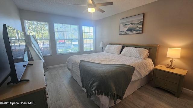 bedroom featuring multiple windows, ceiling fan, a textured ceiling, and light wood-type flooring