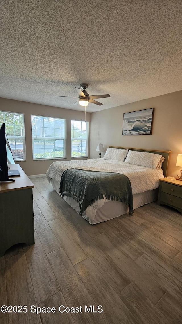 bedroom with hardwood / wood-style flooring, ceiling fan, and a textured ceiling