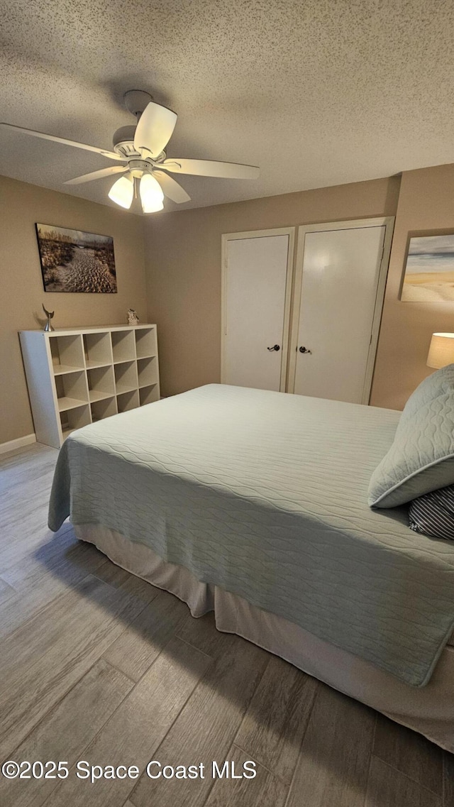 bedroom with a textured ceiling, wood-type flooring, and ceiling fan