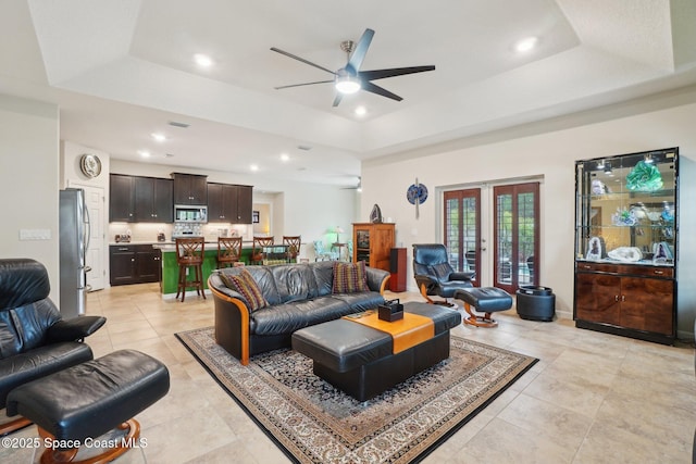 living room featuring light tile patterned floors, a raised ceiling, ceiling fan, and french doors