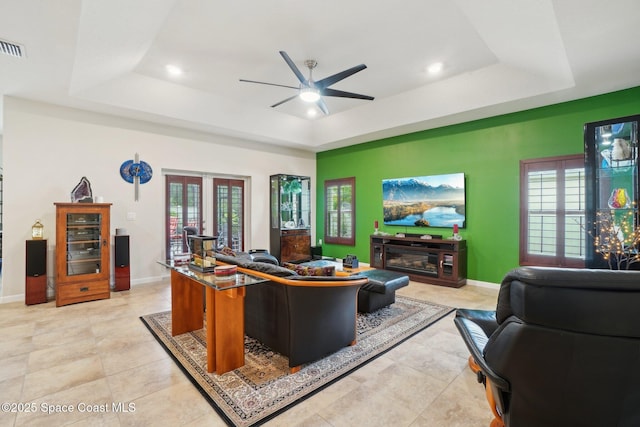 living room featuring light tile patterned floors, a tray ceiling, french doors, and ceiling fan