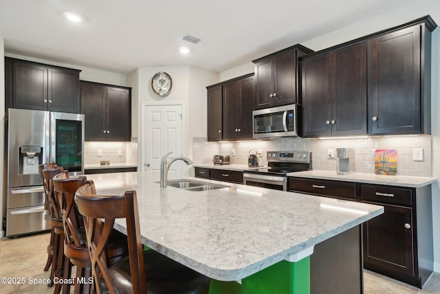 kitchen featuring sink, a kitchen breakfast bar, stainless steel appliances, and an island with sink