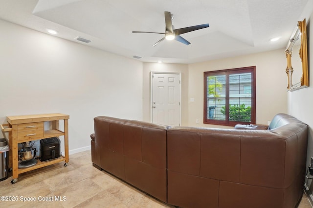 living room featuring ceiling fan and a tray ceiling