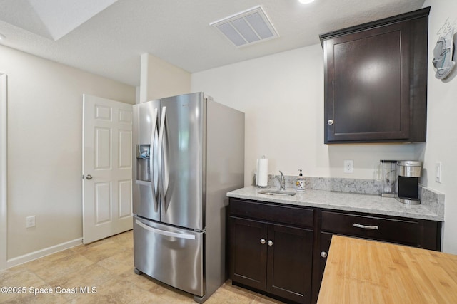 kitchen featuring wood counters, stainless steel fridge with ice dispenser, dark brown cabinets, and sink