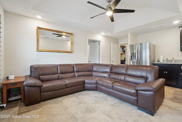 living room with sink, a raised ceiling, and ceiling fan