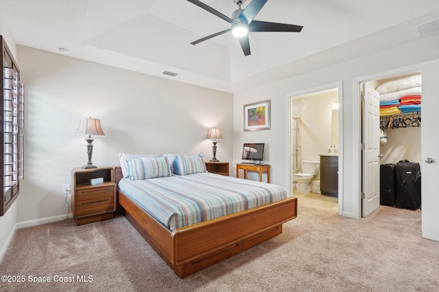 bedroom with a raised ceiling, a walk in closet, light carpet, and a closet