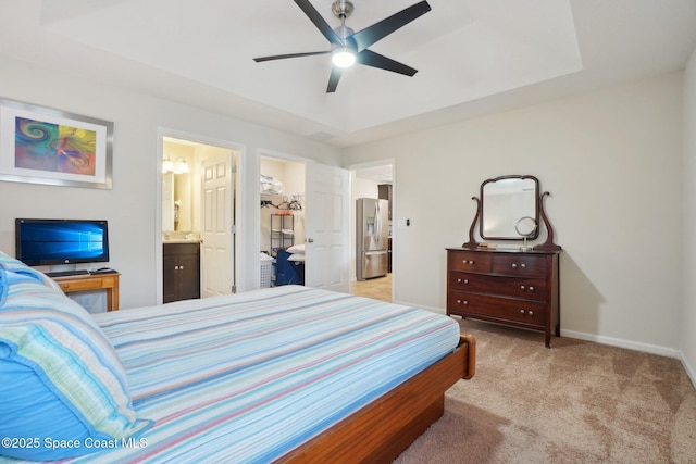 bedroom with stainless steel refrigerator with ice dispenser, light colored carpet, a raised ceiling, and ensuite bath