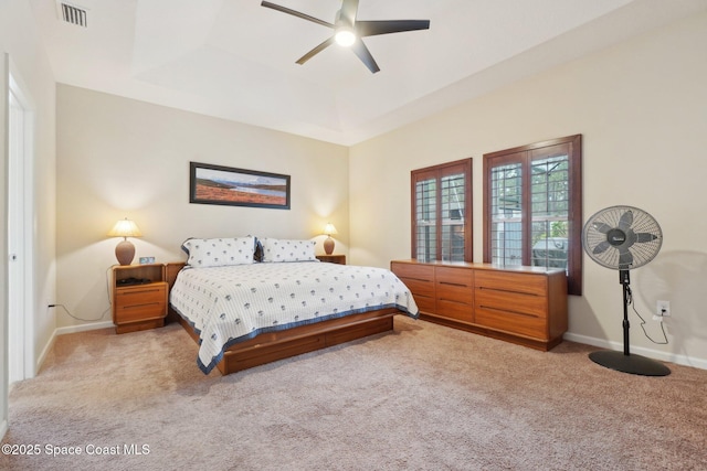 carpeted bedroom with a raised ceiling and ceiling fan