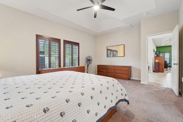 carpeted bedroom featuring ceiling fan and a tray ceiling