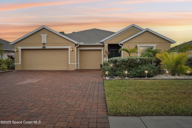 ranch-style home with a garage and a lawn