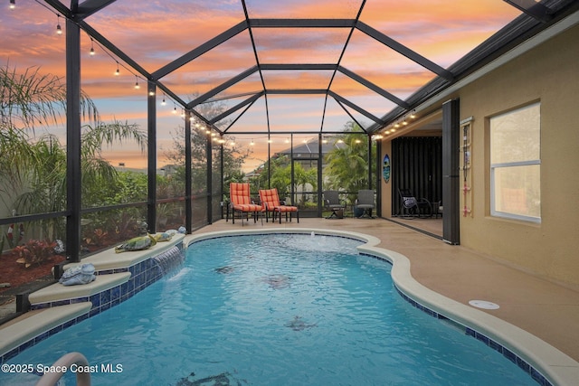 pool at dusk featuring pool water feature, glass enclosure, and a patio area