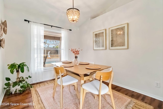 dining room with lofted ceiling, wood-type flooring, and an inviting chandelier