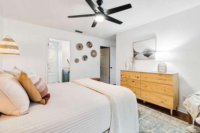 bedroom featuring a textured ceiling, ceiling fan, ensuite bathroom, and dark hardwood / wood-style flooring