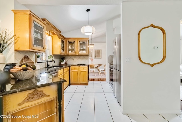 kitchen with light tile patterned floors, decorative backsplash, dark stone countertops, hanging light fixtures, and sink