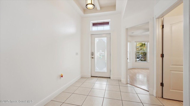 entrance foyer with light tile patterned flooring, a tray ceiling, and plenty of natural light