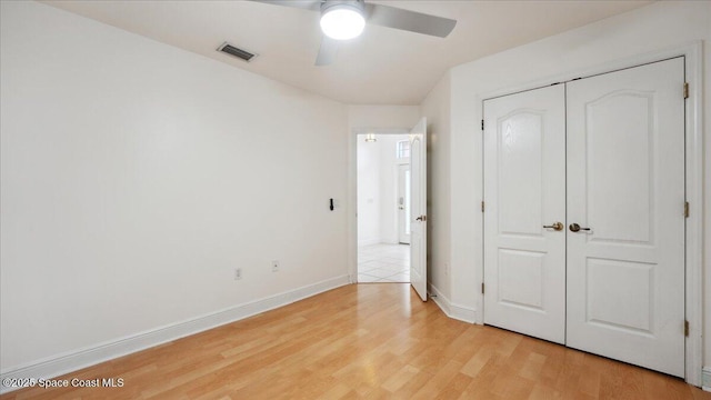 unfurnished bedroom featuring ceiling fan, light wood-type flooring, and a closet