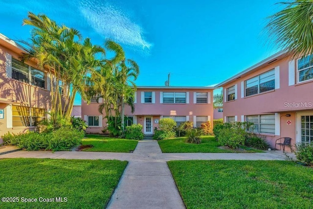 townhome / multi-family property featuring a front yard and stucco siding