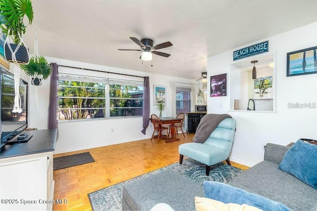 living area featuring ceiling fan and baseboards