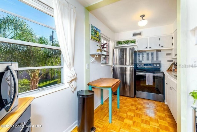 kitchen featuring tasteful backsplash, light countertops, visible vents, appliances with stainless steel finishes, and white cabinets