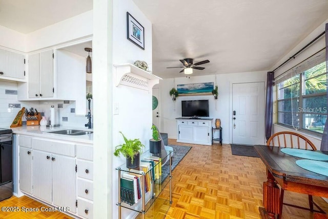 kitchen featuring a sink, white cabinets, open floor plan, light countertops, and tasteful backsplash