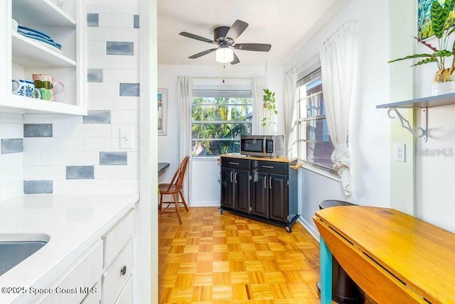 kitchen with a ceiling fan, light countertops, stainless steel microwave, and open shelves