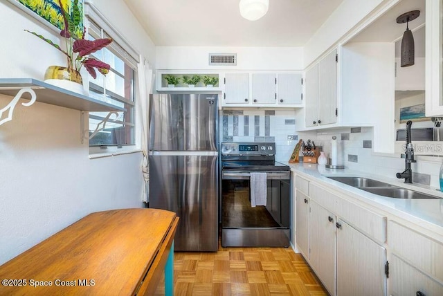 kitchen with visible vents, backsplash, appliances with stainless steel finishes, white cabinetry, and a sink