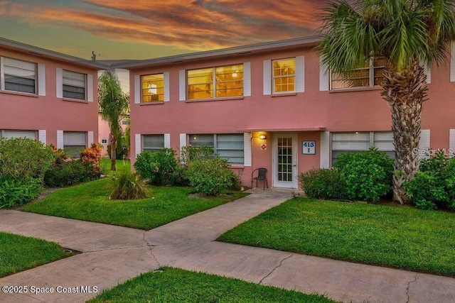 multi unit property with a lawn and stucco siding