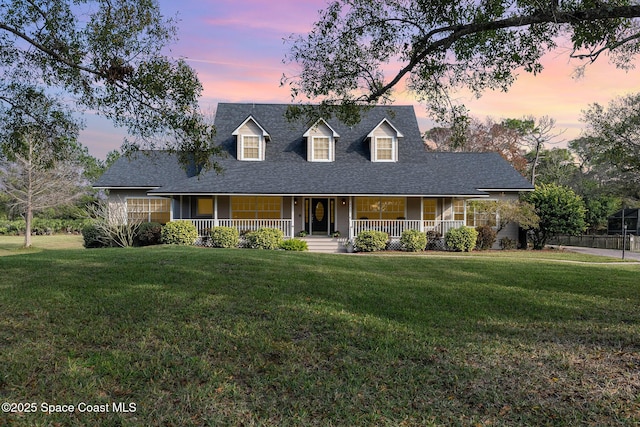 cape cod house with a porch and a yard