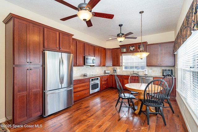 kitchen featuring stainless steel appliances, ceiling fan, tasteful backsplash, and hanging light fixtures