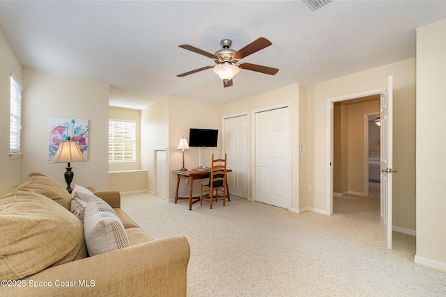 living room with a textured ceiling, ceiling fan, and a wealth of natural light