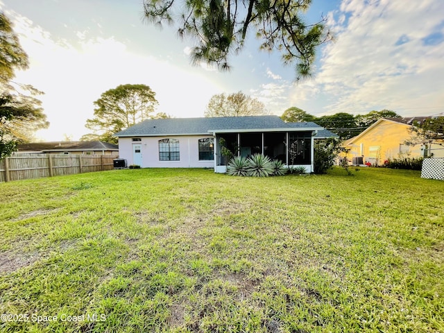 rear view of property with a yard, a sunroom, and central AC unit