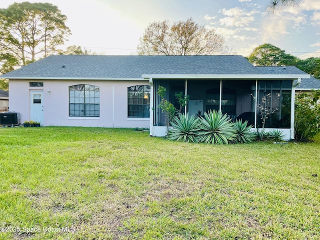 rear view of property with central AC unit, a sunroom, and a yard