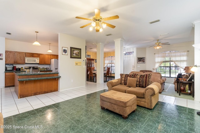 living room with ceiling fan, sink, light tile patterned floors, and ornate columns