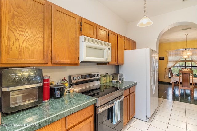 kitchen featuring decorative light fixtures, light tile patterned floors, white appliances, and a chandelier