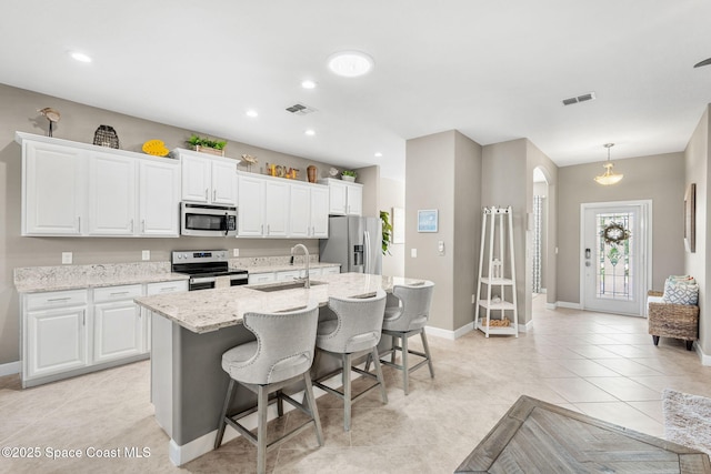 kitchen featuring sink, a kitchen island with sink, white cabinetry, and appliances with stainless steel finishes