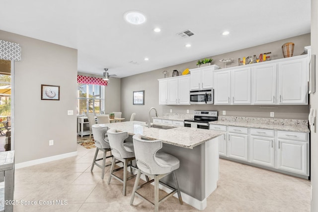 kitchen with appliances with stainless steel finishes, white cabinetry, sink, a breakfast bar, and a center island with sink