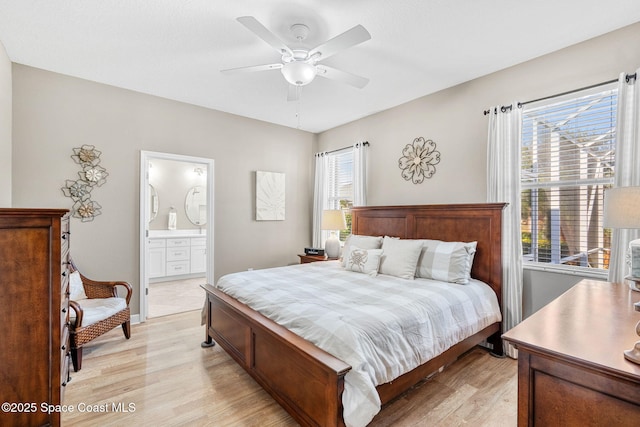 bedroom with light wood-type flooring, ensuite bathroom, multiple windows, and ceiling fan