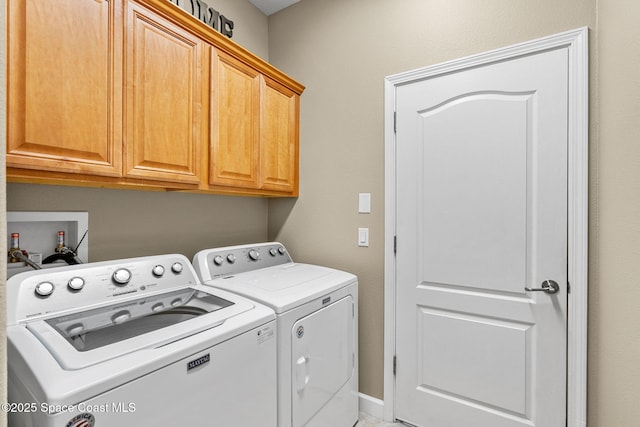 clothes washing area with cabinets and separate washer and dryer