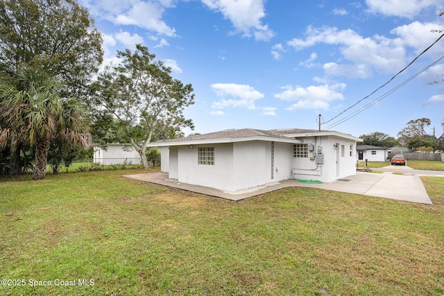 rear view of house featuring a lawn and a patio