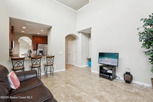 living room featuring a towering ceiling and crown molding