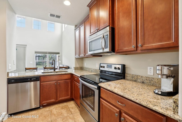 kitchen with sink, stainless steel appliances, and light stone countertops