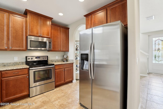 kitchen with light stone counters, appliances with stainless steel finishes, and light tile patterned floors