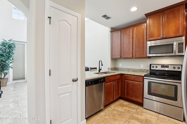 kitchen with stainless steel appliances, sink, and light stone counters