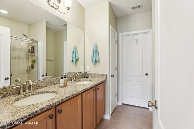 bathroom featuring tile patterned flooring, a textured ceiling, walk in shower, and vanity