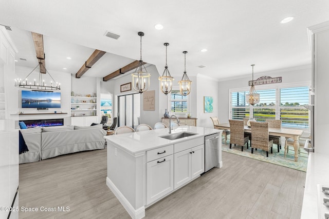 kitchen with white cabinetry, sink, hanging light fixtures, stainless steel dishwasher, and a center island with sink